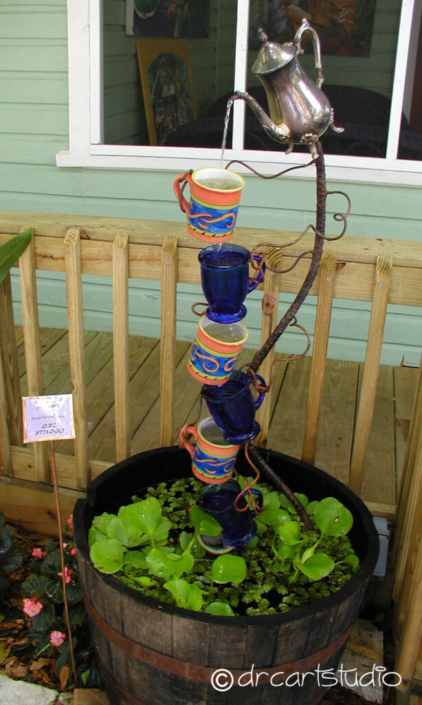 Photo of a hand made fountain, created with an old wine barrel, ceramic coffee cups and copper